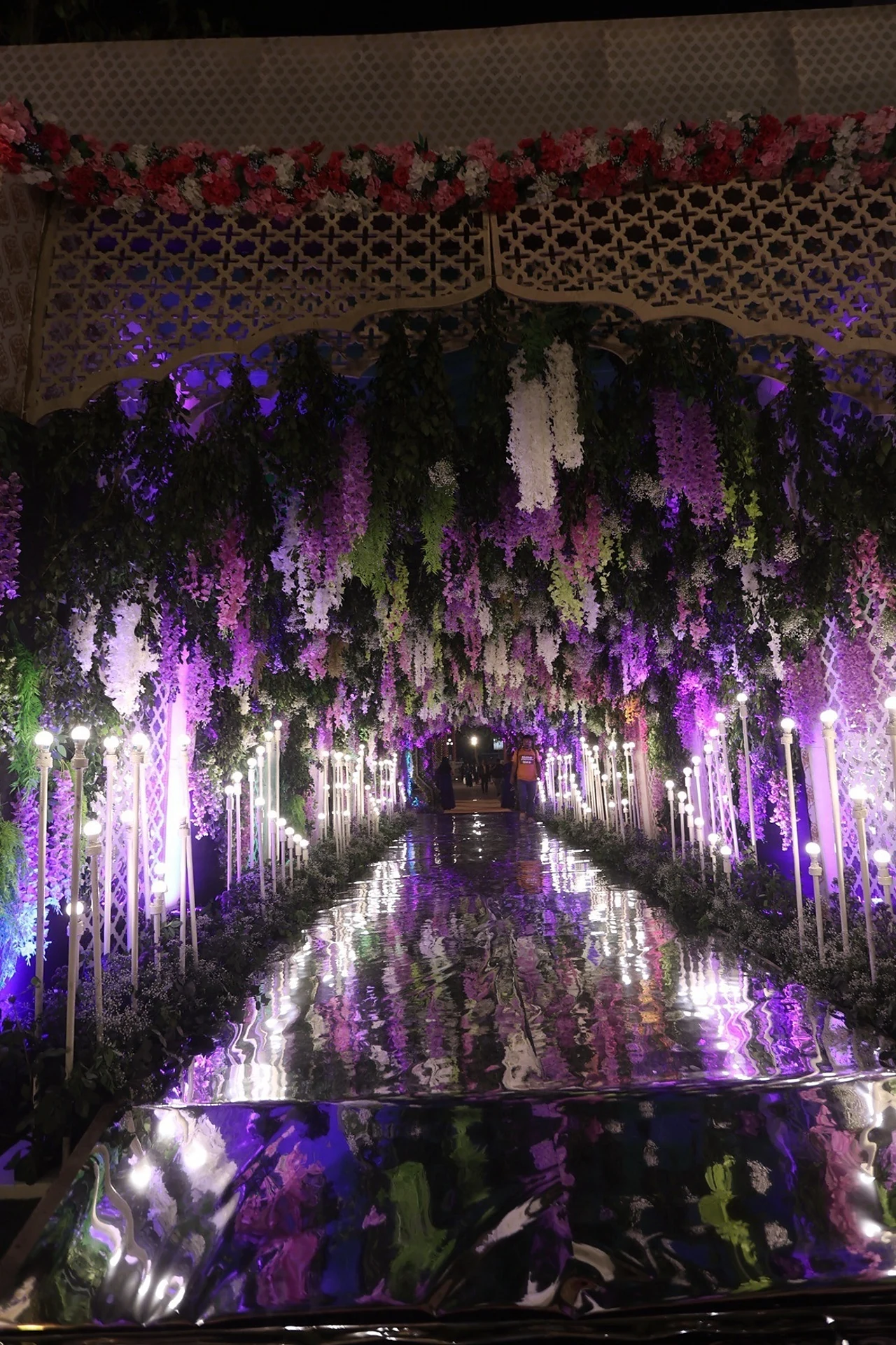 Illuminated purple wisteria mirror tunnel walkway at Divinity Pavilion